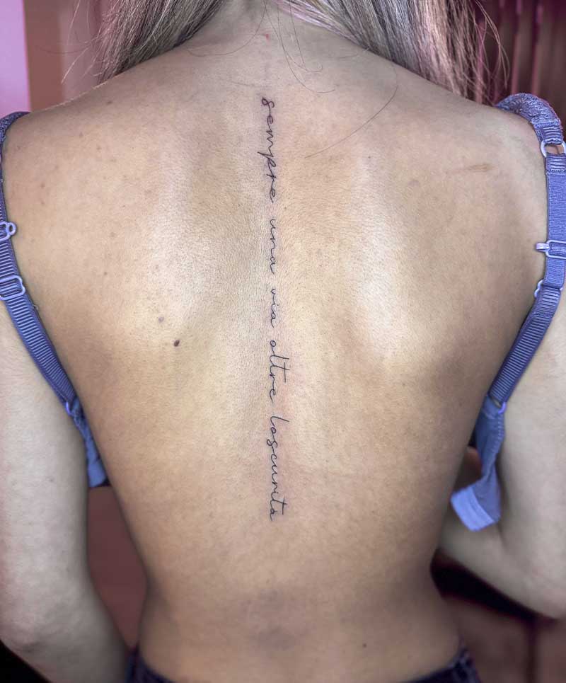 Fineline tekst tattoo 'sempre una via oltre l'oscurità' op de ruggengraat.
