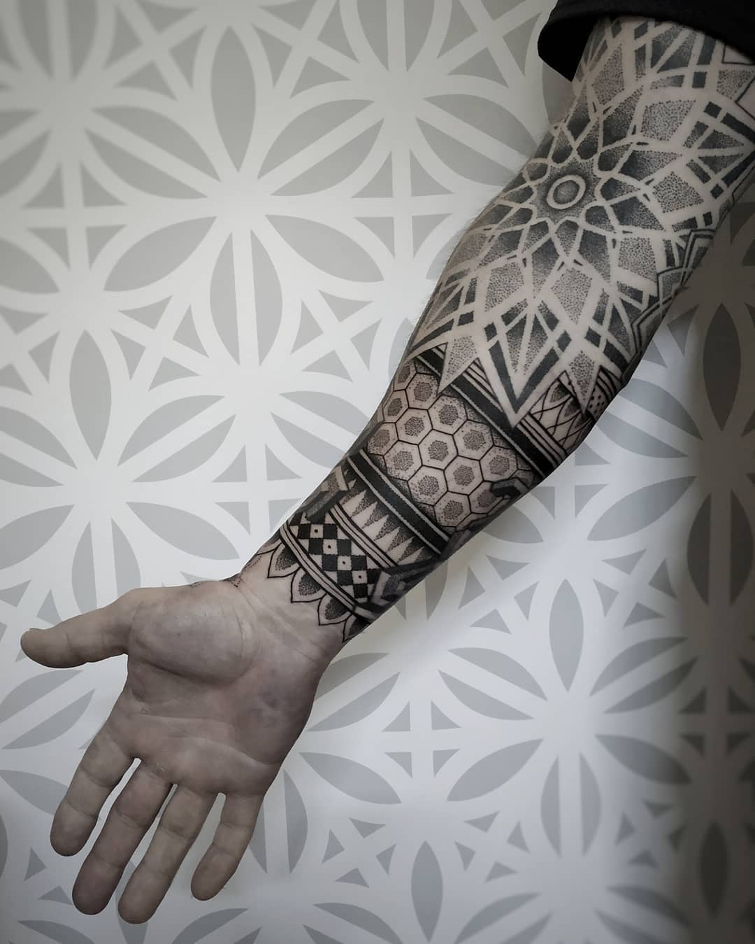 Geometrische dotwork sleeve met mandala en patronen op de onderarm.