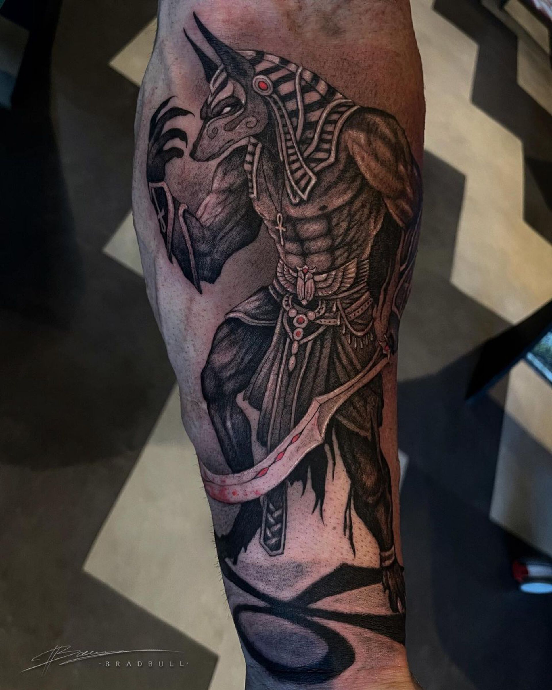 Gedetailleerde illustratieve tattoo van de Egyptische god Anubis op het onderbeen.