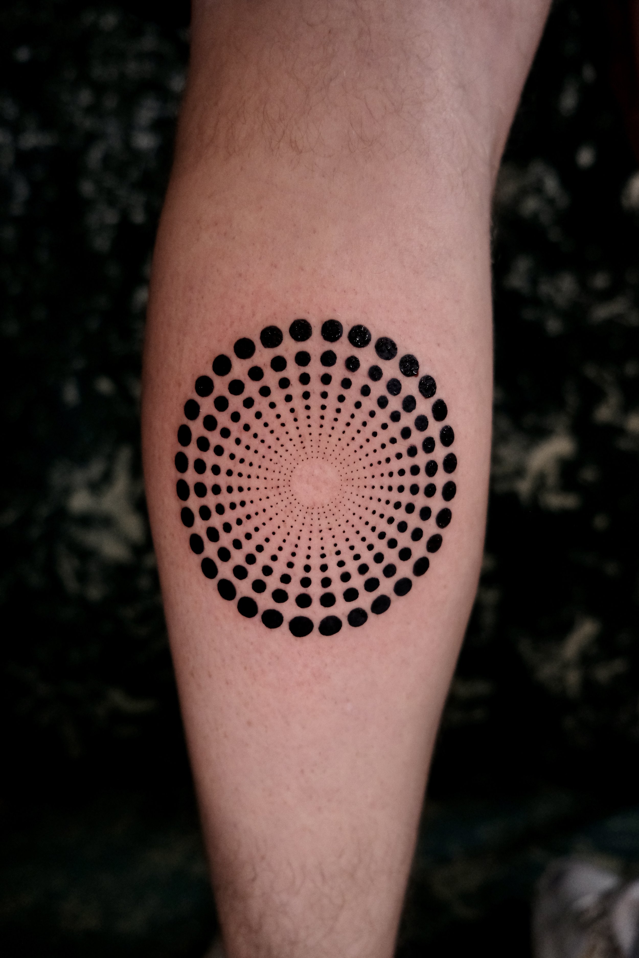 Cirkelvormig patroon van zwarte stippen met optische diepte op onderbeen.
