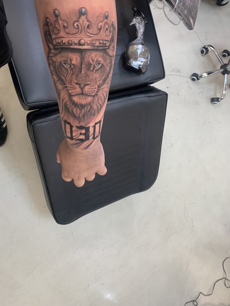 Realistische leeuw met kroon en '030' tekst op onderarm.