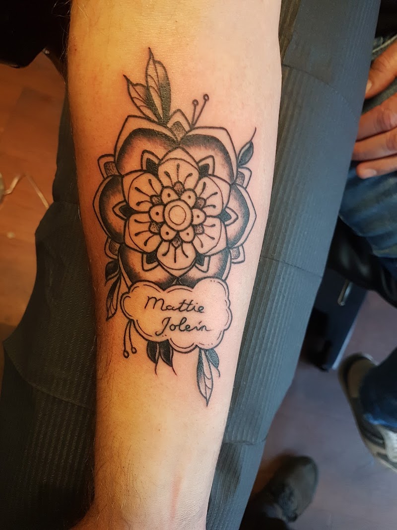 Blackwork mandala bloem met namen 'Mattie Jolein' in een wolkje op de onderarm.