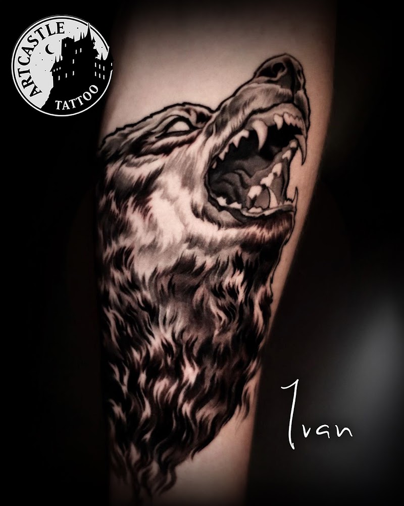 Realistische huilende wolf in zwart-wit op onderarm.