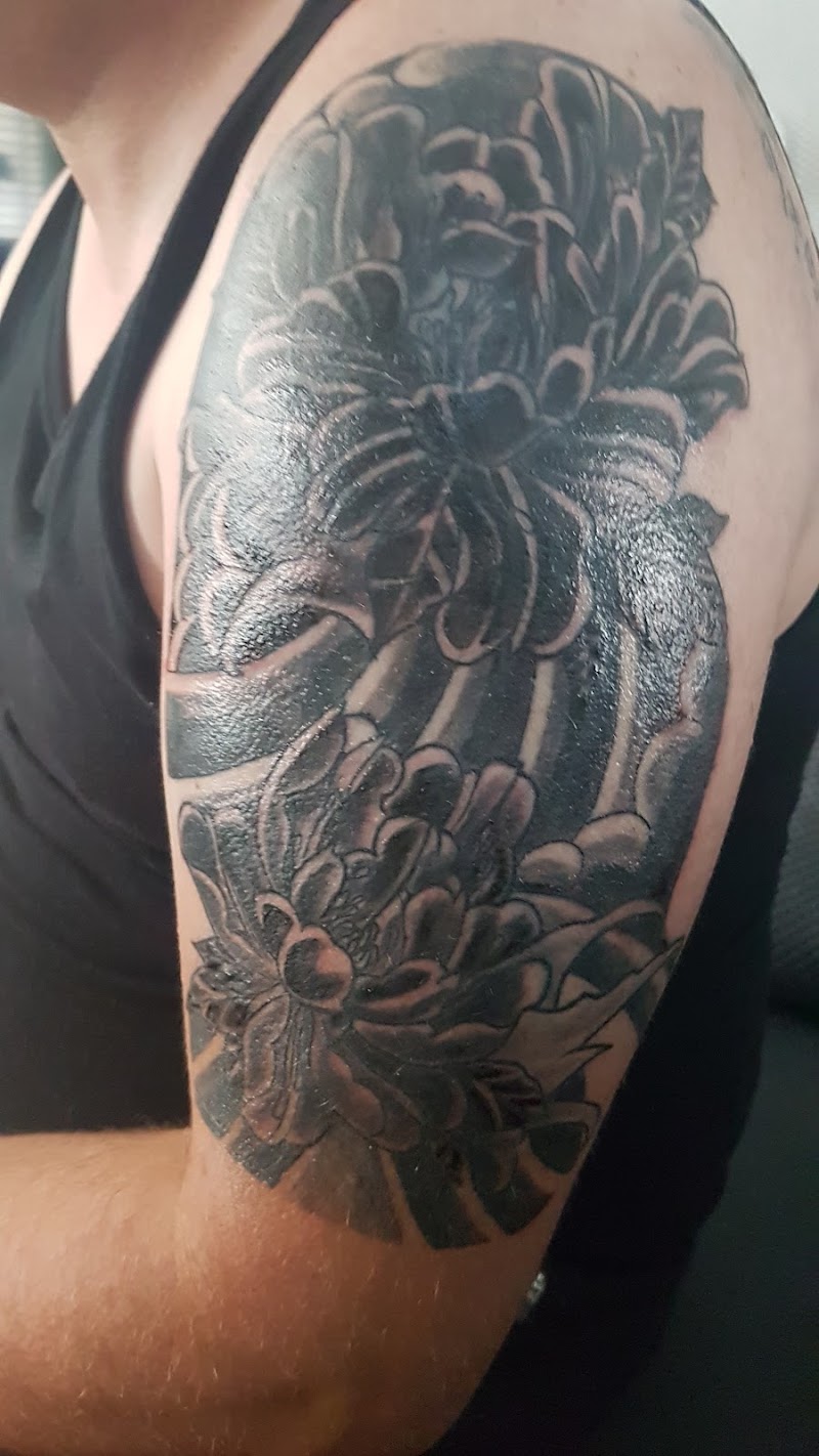 Blackwork half-sleeve met Japanse bloemen (chrysanten) en golven op bovenarm.