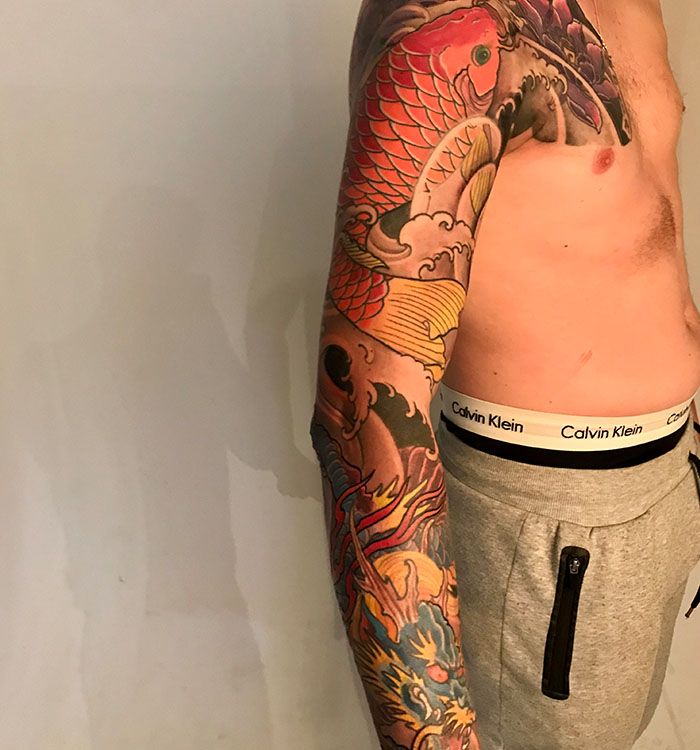 Kleurrijke Japanse sleeve tattoo met koi karper en draak.