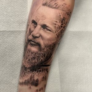 Realistisch portret van Ragnar Lothbrok met Viking symbolen en boslandschap.