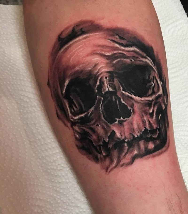 Realistische zwart-grijze schedel tattoo op onderbeen.