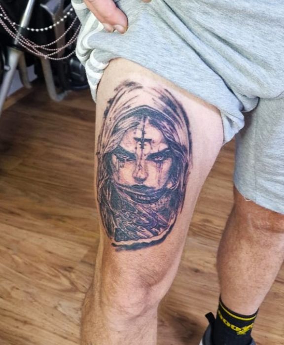 Zwart-wit portret van een duistere, gehuifde figuur met een kruis op het voorhoofd.