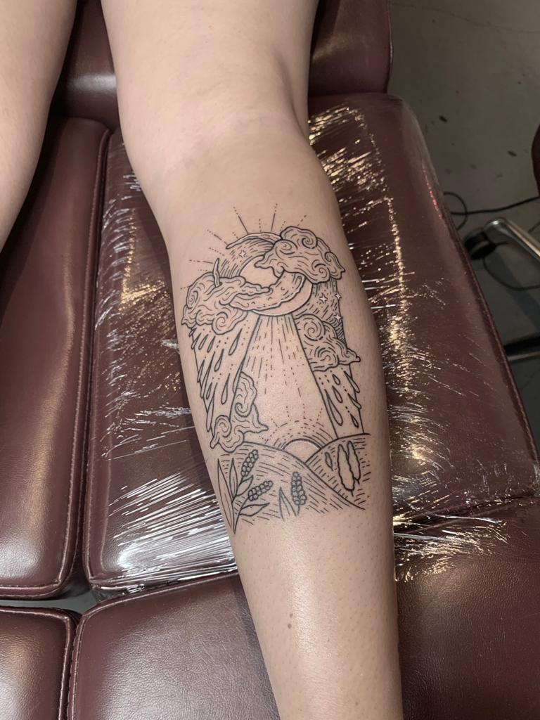 Fineline landschap met zon, wolken, regen en planten op onderbeen.